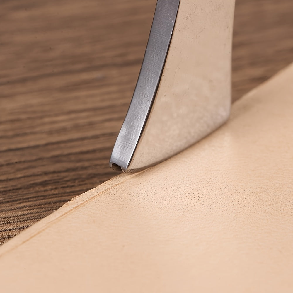 Leather edge creaser tool with metal blade pressing a pale tan leather edge
