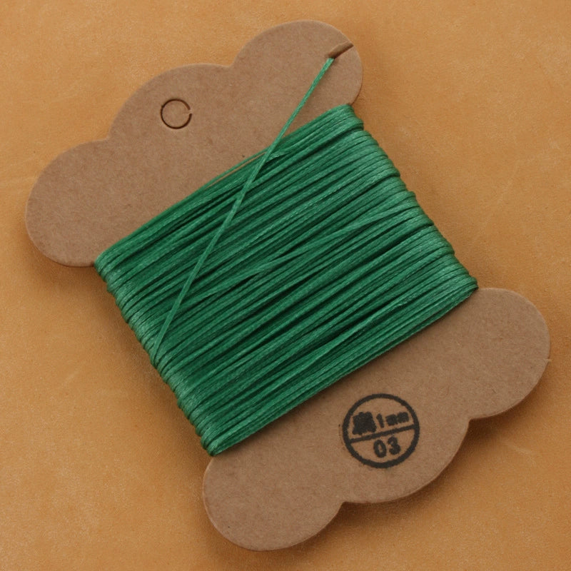 Waxed polyester thread spool in deep green on cardboard card