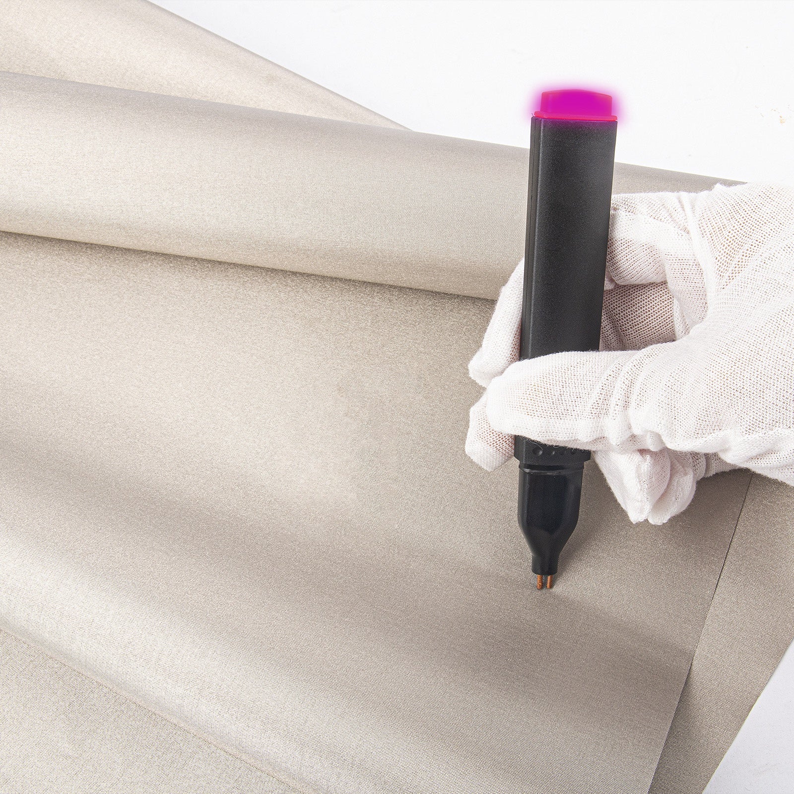 Beige shielding fabric laid on a surface with a rolled edge and applicator tool