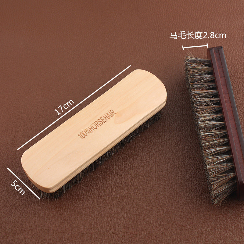 Horsehair leather brush with light wooden handle and dense dark bristles, angled view