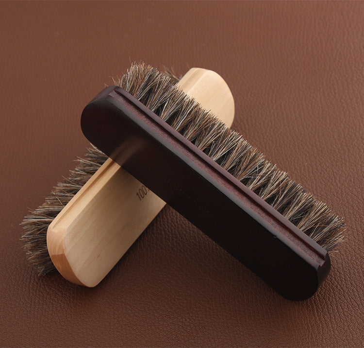 Leather horsehair brush with dark handle and light wooden base, dense dark bristles
