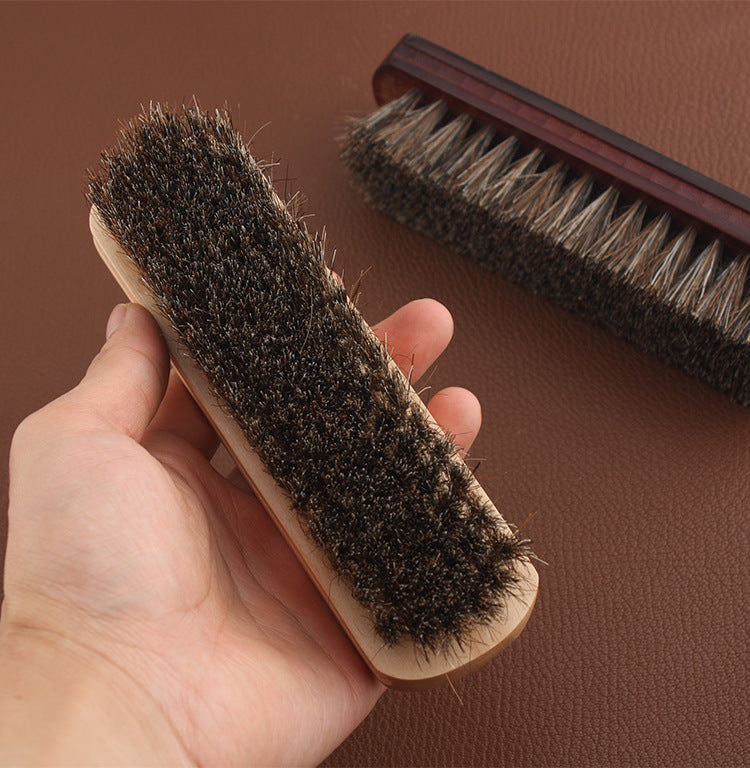 Wood-handled horsehair brush with dark bristles, held in a hand