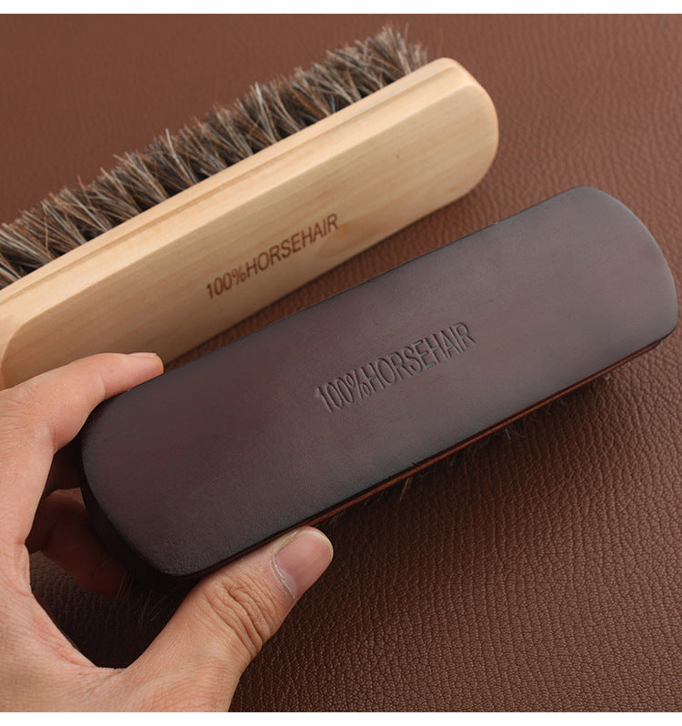 Leather horsehair brush with dark handle and dense bristles, held in hand