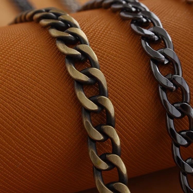 Metal bag chain strap close-up, twisted links with alternating dark and bronze tones
