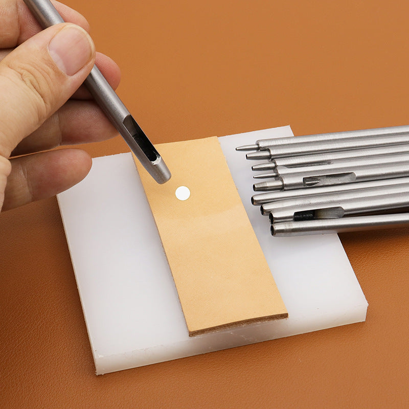 Hand using a round hole punch tool on a leather strap piece