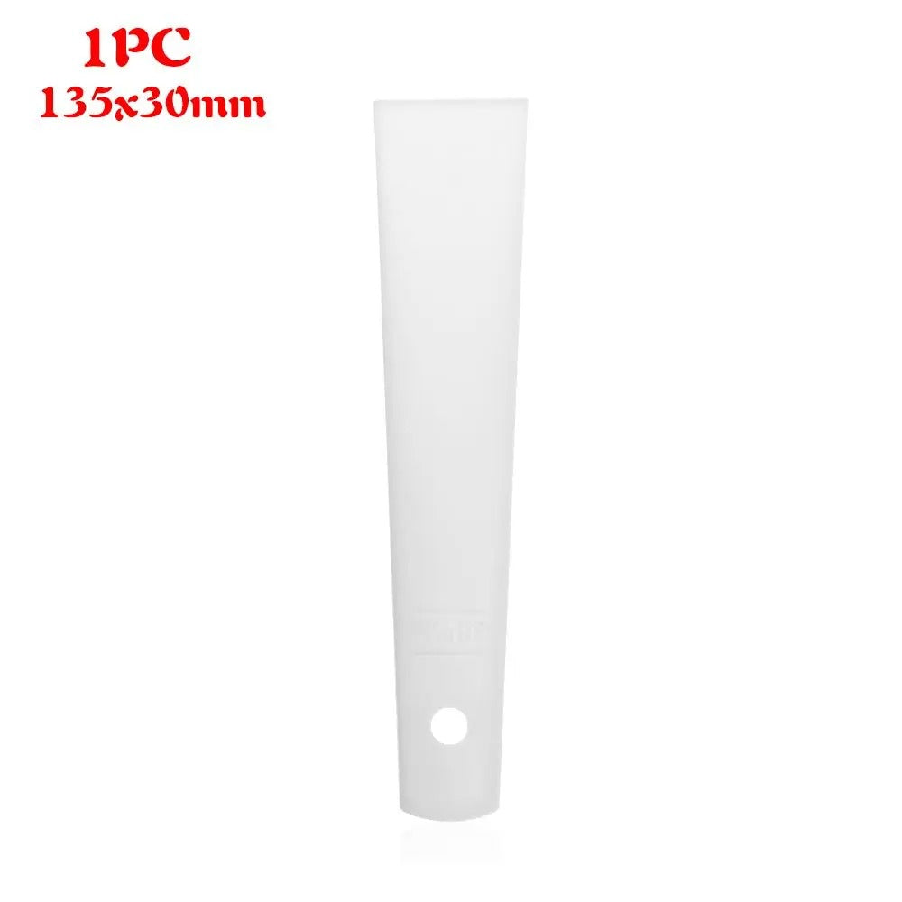 White plastic glue applicator strip with hanging hole at base, smooth flat blade