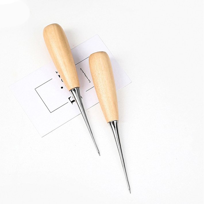 Leather scratch awls with light wood handles and pointed metal tips on template paper