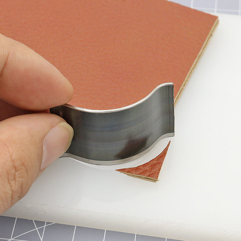 Hands holding steel corner rounding die punch trimming leather edge, rounded corner