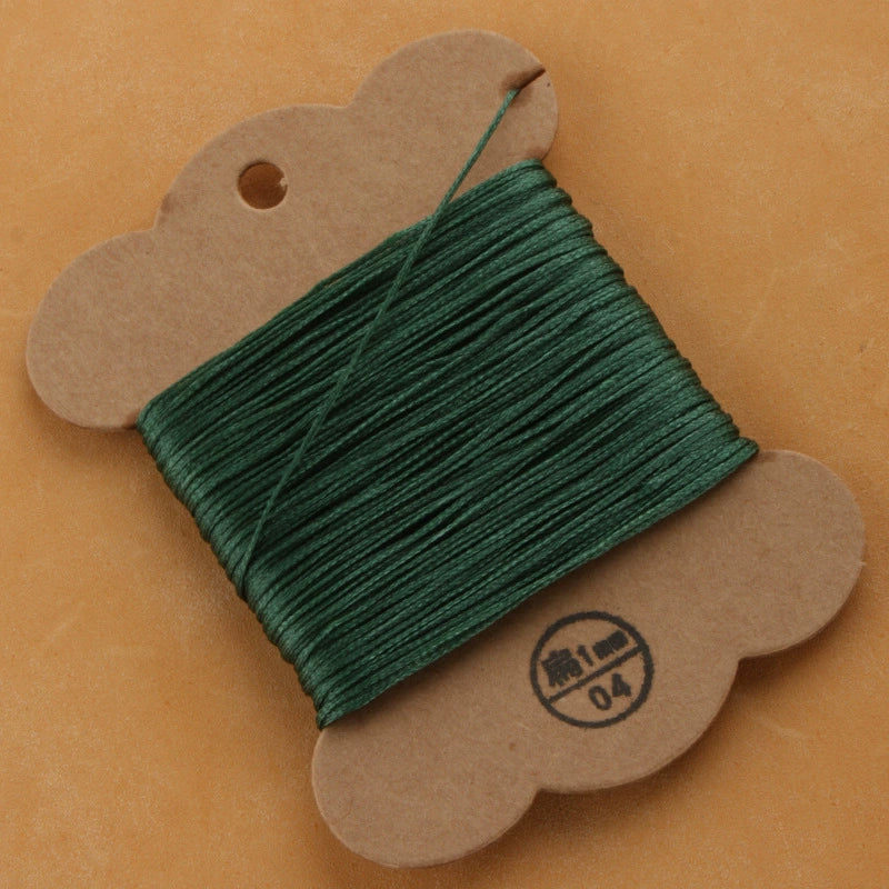 Waxed polyester thread spool in forest green on cardboard card