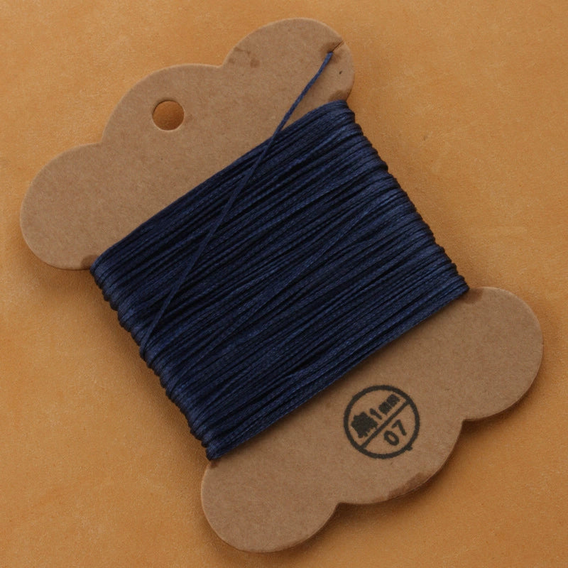 Waxed polyester thread spool in navy blue on cardboard card