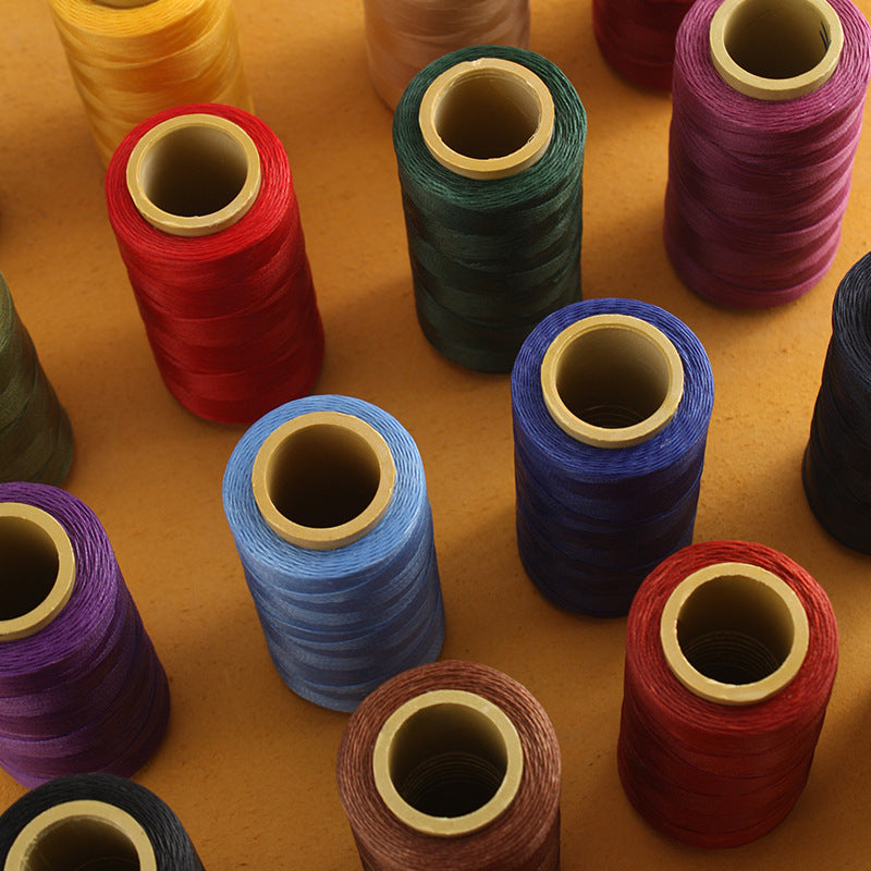 Assorted colored waxed polyester thread spools on tabletop