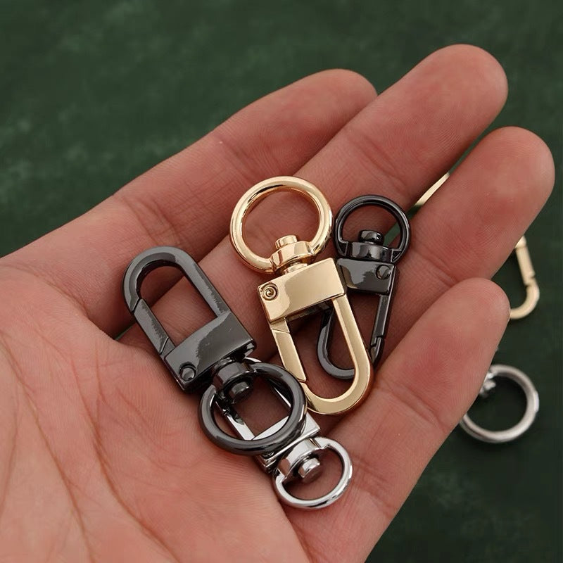 Small swivel hook bag clasps on hand, mixed gold and dark metal finishes