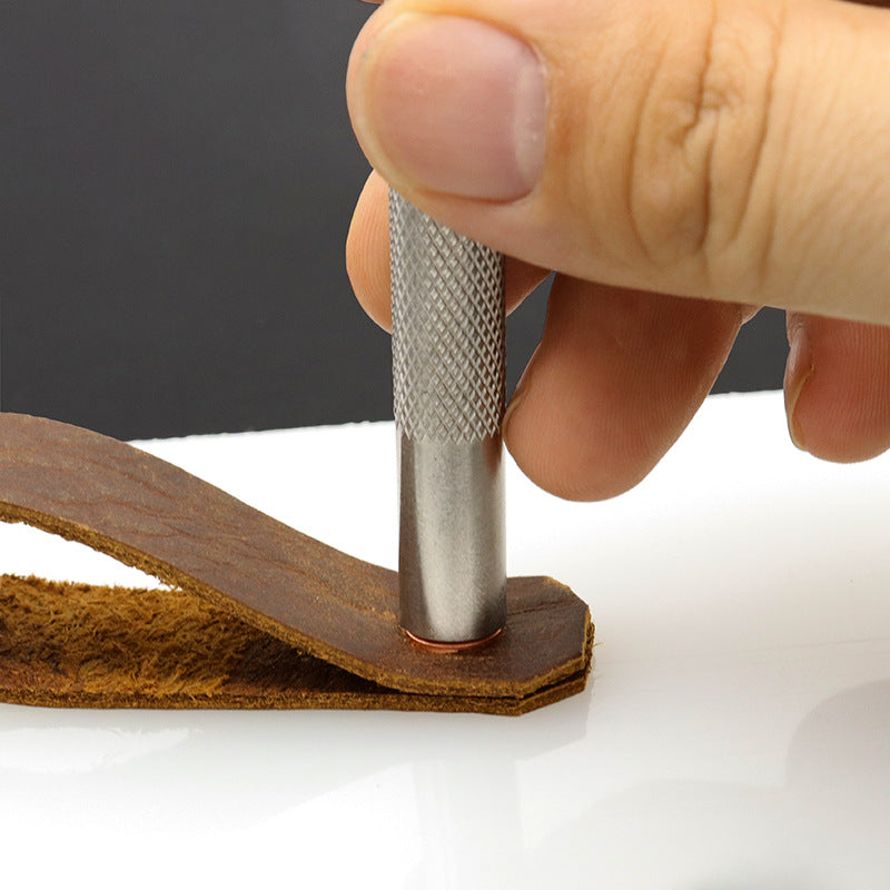 Metal rivet setter tool pressing into a leather piece near a pre-made hole