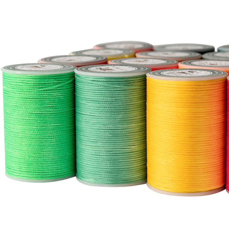 Flat waxed thread spools in green, teal, and orange on a roll