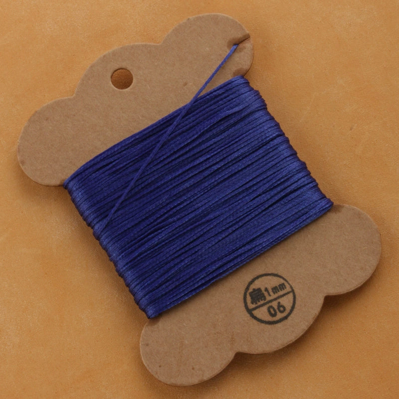 Waxed polyester thread spool in purple on cardboard card