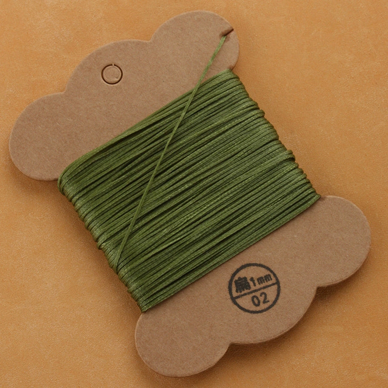 Waxed polyester thread spool in dark green on cardboard card