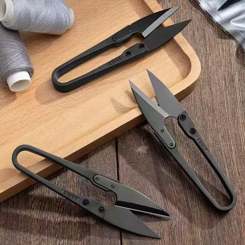 Thread cutter nippers with black loop handles and pointed blades on wooden board